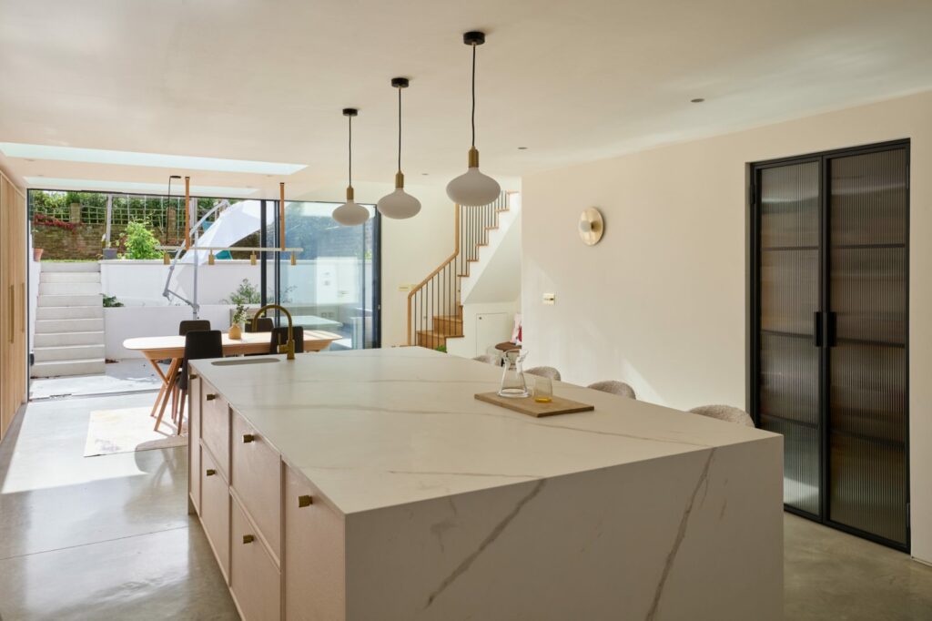 Bright kitchen extension with marble island and pendant lights
