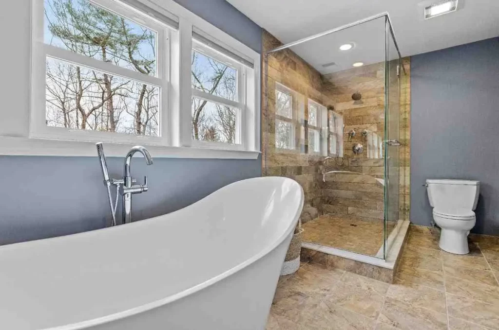Cost of Renovation of Bathroom featuring a modern bathroom with freestanding bathtub, walk-in glass shower, tiled flooring, and contemporary fixtures in a UK home