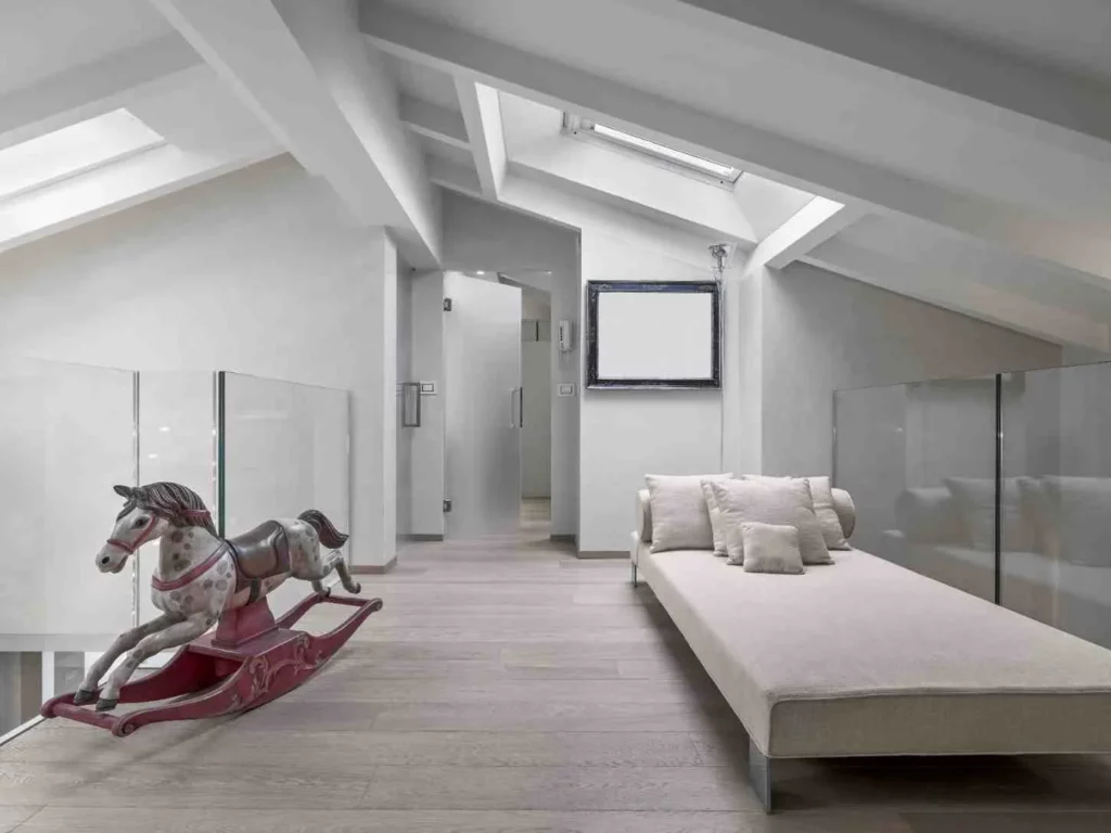 Hip to Gable Loft Conversions interior with vaulted white-beamed ceiling, skylight windows, glass balustrades, wooden flooring, modern chaise lounge, and spacious attic living area filled with natural light.