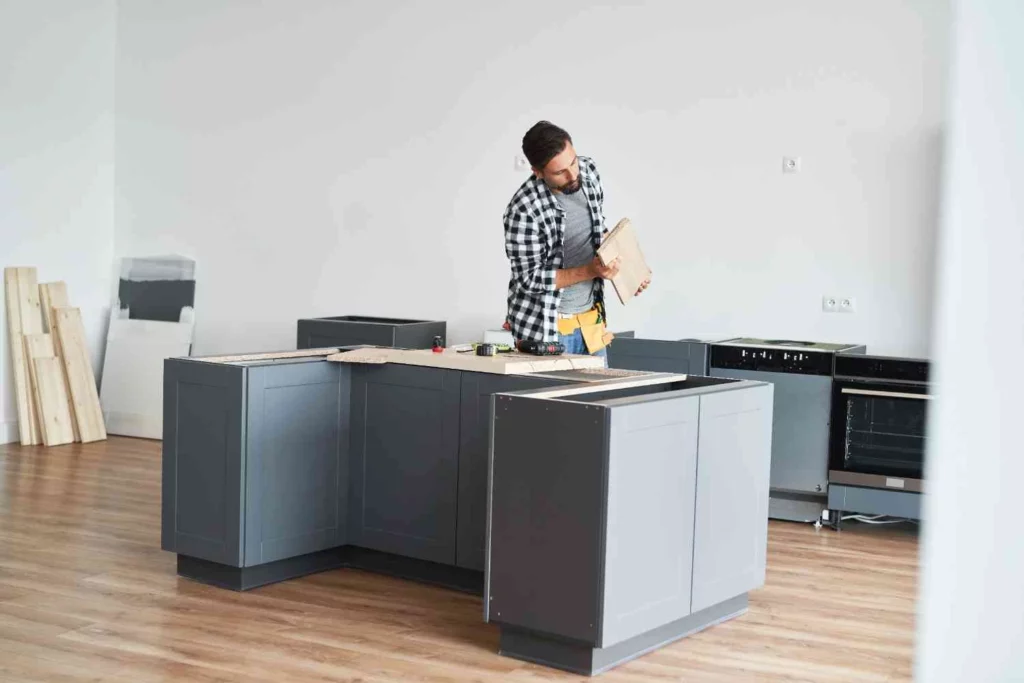 How Much Does It Cost to Fit a Kitchen – professional kitchen fitter installing modern kitchen cabinets during a UK home renovation.