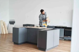 How Much Does It Cost to Fit a Kitchen – professional kitchen fitter installing modern kitchen cabinets during a UK home renovation.