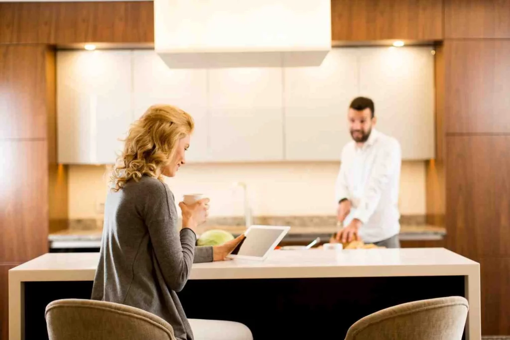 Couple reviewing kitchen designer cost estimate on tablet in modern wood kitchen