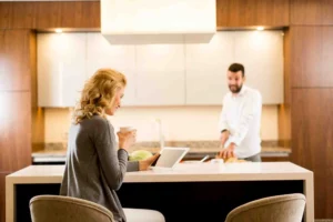 Couple reviewing kitchen designer cost estimate on tablet in modern wood kitchen
