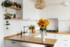 Kitchen Makeovers on a Budget featuring white cabinets, wooden worktops, open shelving, modern lighting, and fresh sunflowers in a bright contemporary kitchen.