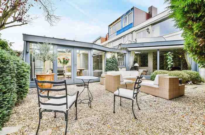 Rear House Extension Ideas featuring a modern glass rear extension with an open-plan kitchen extension, large sliding doors, contemporary outdoor seating, and a stylish UK home design.