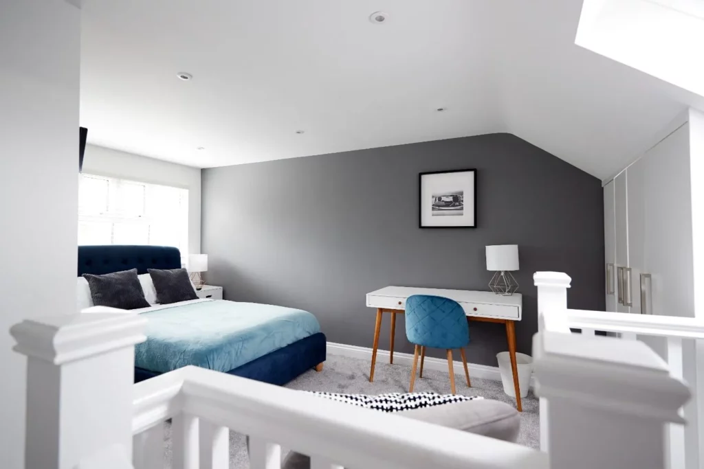 Modern loft bedroom created by converting a loft into a bedroom, featuring a double bed, fitted wardrobes, a desk, and a skylight.